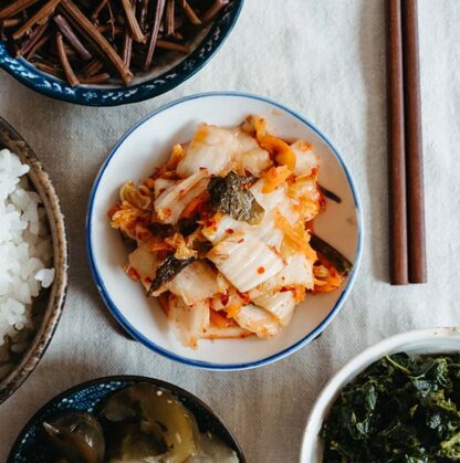 A closeup of a bowl of kimchi surrounded by other side dishes