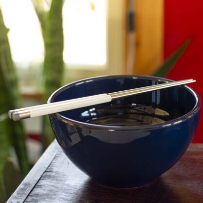 White Korean chopsticks on top of a blue ceramic bowl