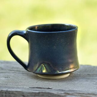 Bronze and dark brown ceramic mug with a tent carved at the bottom near the handle